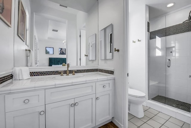 bathroom featuring a shower with shower door, toilet, vanity, and tile patterned flooring