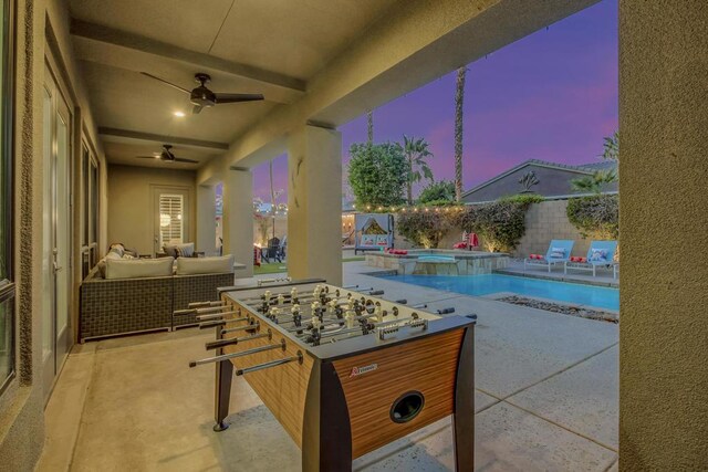 patio terrace at dusk featuring ceiling fan, a swimming pool with hot tub, and outdoor lounge area