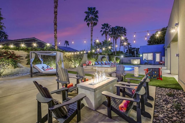 patio terrace at dusk featuring a fenced in pool and an outdoor fire pit