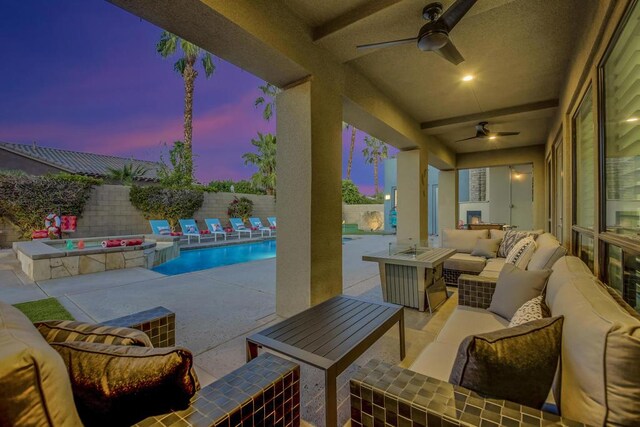 patio terrace at dusk featuring ceiling fan, a swimming pool with hot tub, and an outdoor living space