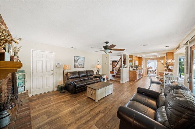 living room with a fireplace, ceiling fan with notable chandelier, and hardwood / wood-style floors