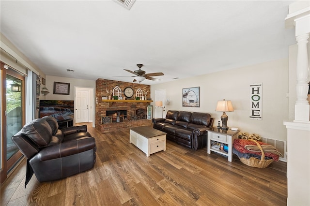 living room with ceiling fan, dark wood-type flooring, ornate columns, and a fireplace