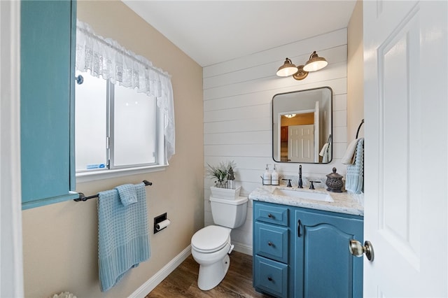 bathroom featuring toilet, vanity, wood walls, and hardwood / wood-style flooring