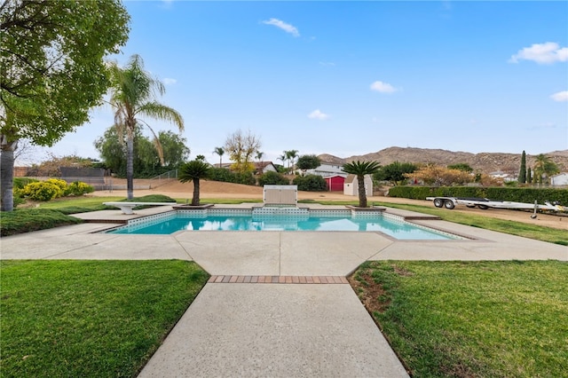 view of pool with a diving board, a patio area, a lawn, a storage shed, and a mountain view