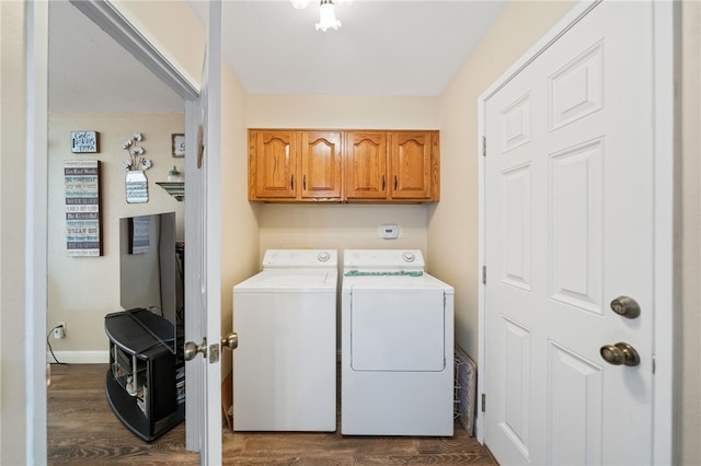 washroom featuring dark hardwood / wood-style floors, washing machine and clothes dryer, and cabinets