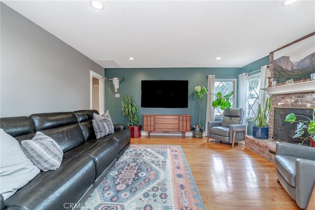 living room with light wood-type flooring and a brick fireplace