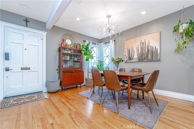 dining space with beam ceiling, a notable chandelier, and hardwood / wood-style floors