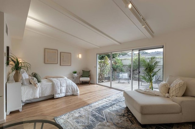 bedroom featuring hardwood / wood-style flooring, access to exterior, rail lighting, and vaulted ceiling with beams