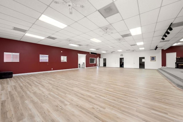 workout area featuring a paneled ceiling and light wood-type flooring