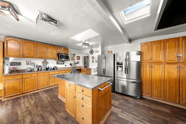 kitchen with dark wood-type flooring, appliances with stainless steel finishes, a center island, and a skylight