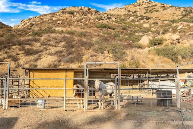 view of horse barn featuring a rural view and a mountain view