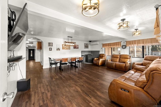 living room with ceiling fan, dark hardwood / wood-style flooring, beamed ceiling, and a wall mounted air conditioner