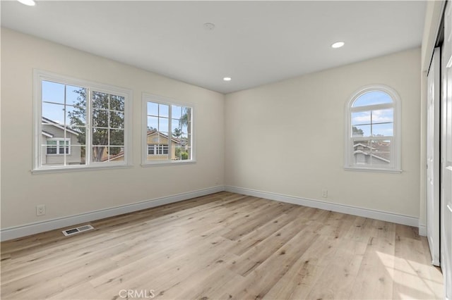 spare room with a wealth of natural light and light hardwood / wood-style flooring