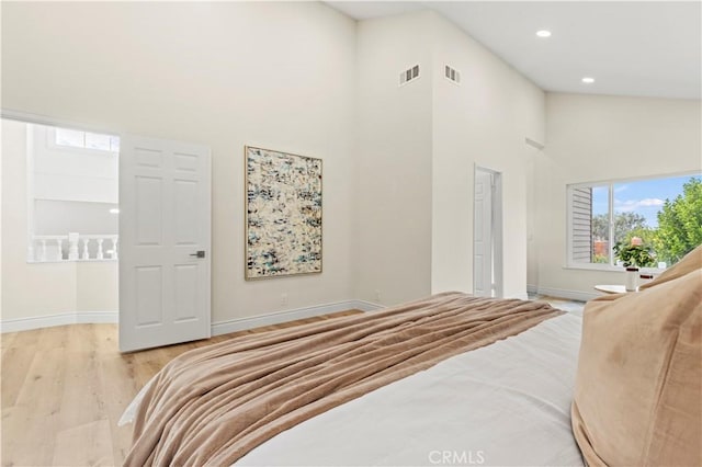 bedroom featuring light wood-type flooring and high vaulted ceiling