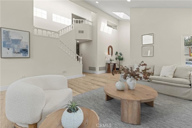 living room with a high ceiling, a skylight, a wealth of natural light, and hardwood / wood-style flooring