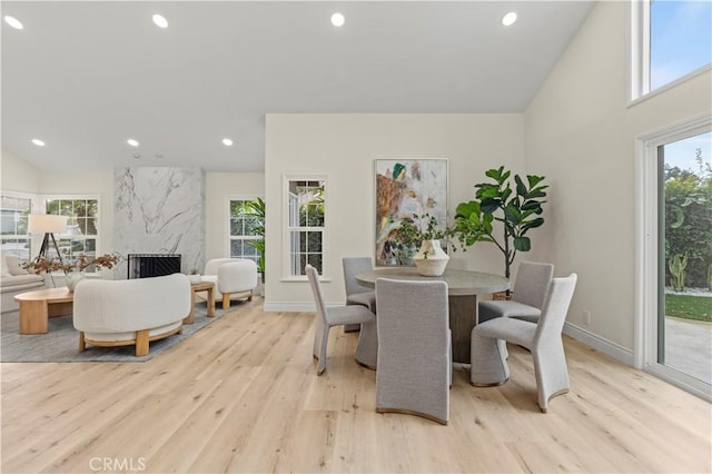 dining area featuring light wood-type flooring, a premium fireplace, and lofted ceiling