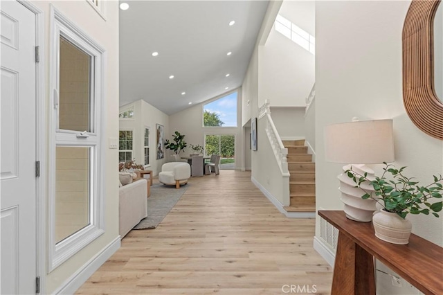 entryway with high vaulted ceiling and light hardwood / wood-style floors