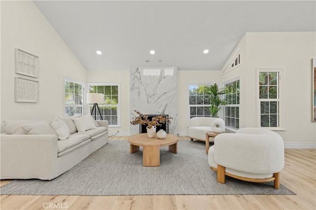 living room with high vaulted ceiling, a premium fireplace, and light hardwood / wood-style flooring