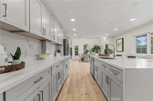 kitchen featuring appliances with stainless steel finishes, tasteful backsplash, light hardwood / wood-style floors, sink, and gray cabinets