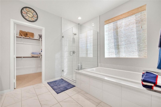 bathroom with baseboards, a garden tub, a spacious closet, and a shower stall