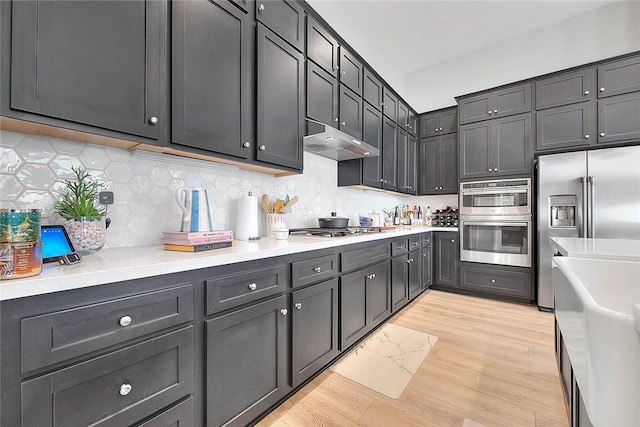 kitchen featuring under cabinet range hood, stainless steel appliances, light countertops, and dark cabinets