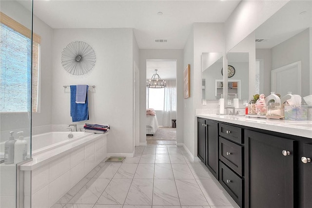 bathroom featuring tiled bath, a notable chandelier, and vanity