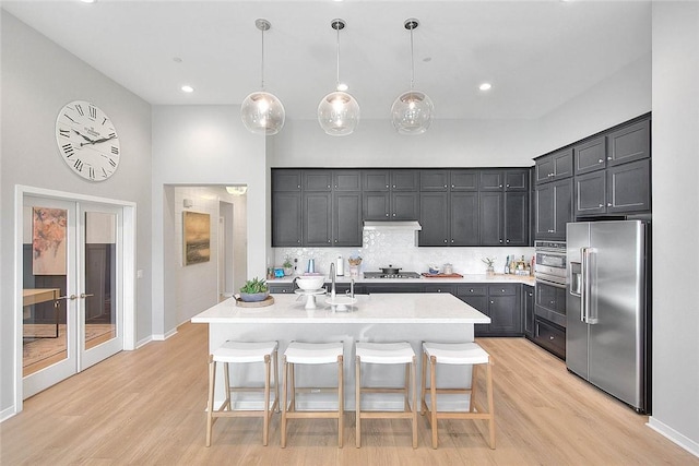 kitchen featuring pendant lighting, appliances with stainless steel finishes, a kitchen island with sink, and a breakfast bar area