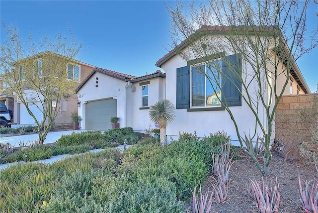 view of side of home with an attached garage, a tile roof, and stucco siding