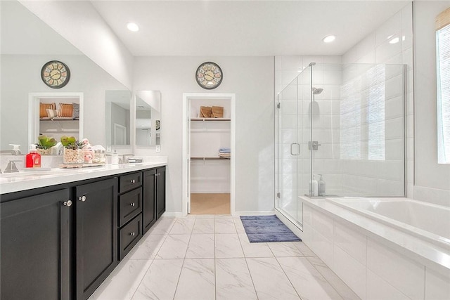 bathroom featuring a sink, marble finish floor, a spacious closet, double vanity, and a stall shower