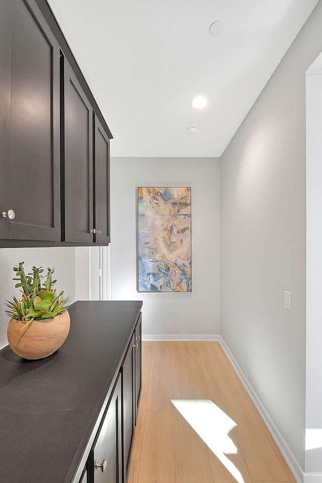 kitchen with light wood-type flooring, dark countertops, and baseboards