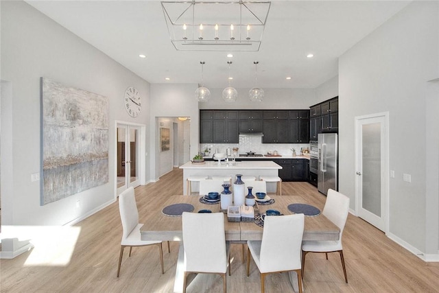 dining space featuring a high ceiling and light hardwood / wood-style flooring