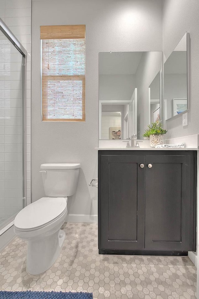 full bathroom with toilet, a sink, baseboards, a shower stall, and double vanity