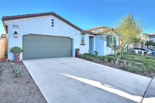 mediterranean / spanish home featuring concrete driveway, an attached garage, a tile roof, and stucco siding