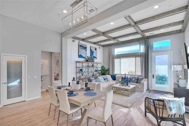 dining room with coffered ceiling, light wood-type flooring, a high ceiling, beam ceiling, and an inviting chandelier