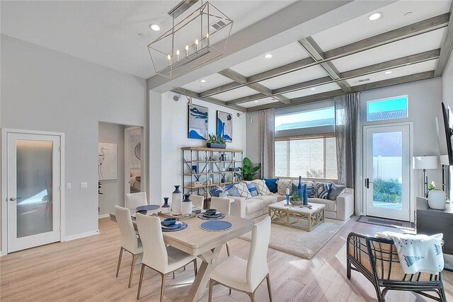 dining space featuring light wood-style flooring, a high ceiling, and coffered ceiling