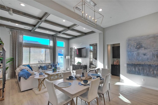 dining space featuring coffered ceiling, visible vents, a towering ceiling, light wood finished floors, and beamed ceiling