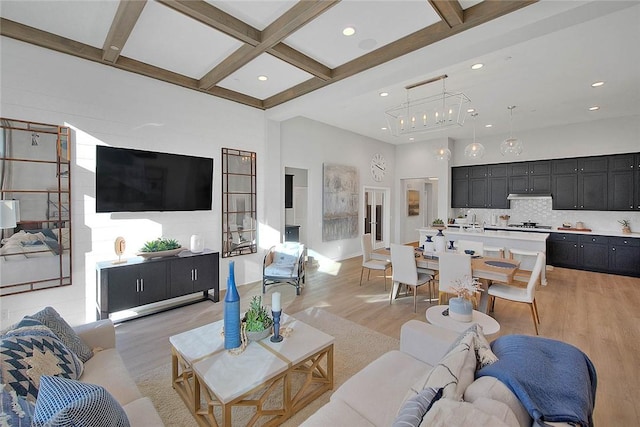 living area featuring light wood finished floors, coffered ceiling, beamed ceiling, a high ceiling, and recessed lighting