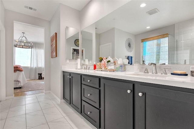 bathroom with vanity, a notable chandelier, and a healthy amount of sunlight