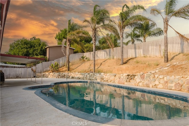 pool at dusk with a patio area