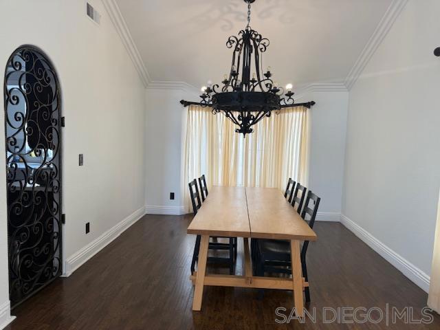 dining area featuring dark hardwood / wood-style floors, ornamental molding, and a notable chandelier