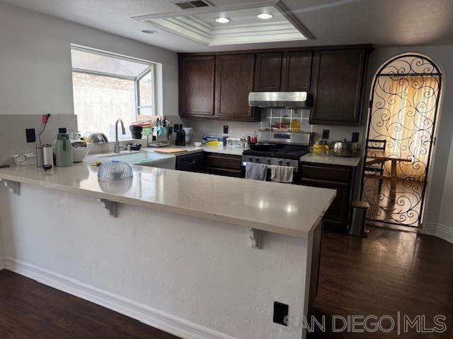 kitchen featuring kitchen peninsula, stainless steel range oven, and a kitchen bar