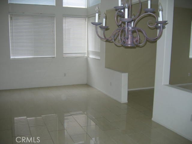 unfurnished dining area with an inviting chandelier and tile patterned flooring