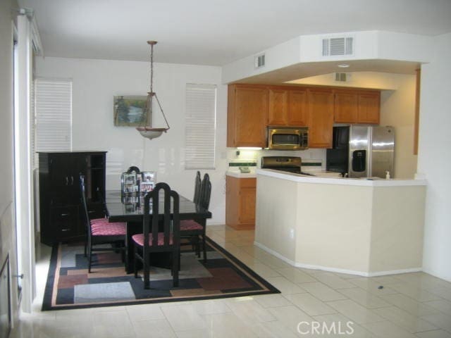 kitchen with hanging light fixtures, light tile patterned floors, and stainless steel appliances