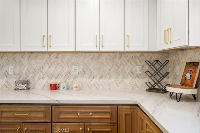 kitchen featuring white cabinetry, decorative backsplash, and light stone counters