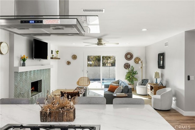 living room with ceiling fan, wood-type flooring, and a fireplace