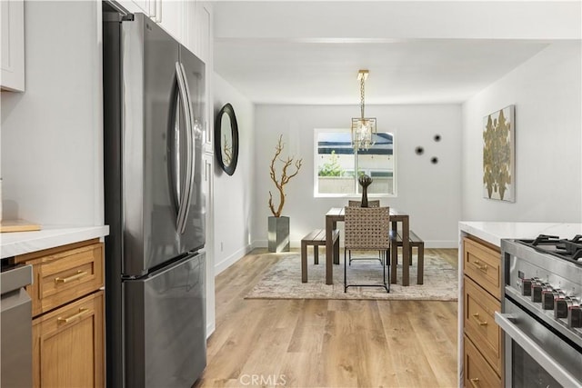 kitchen featuring pendant lighting, white cabinets, stainless steel appliances, and light wood-type flooring