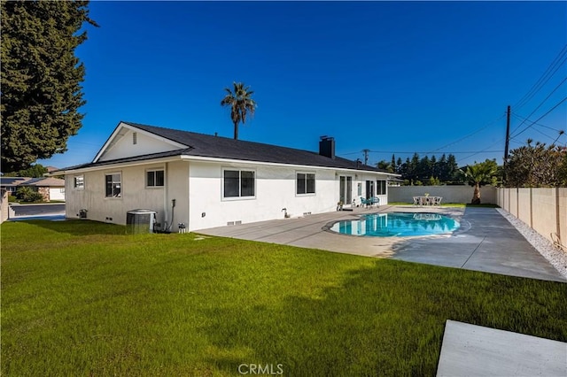 rear view of property with a lawn, a fenced in pool, cooling unit, and a patio