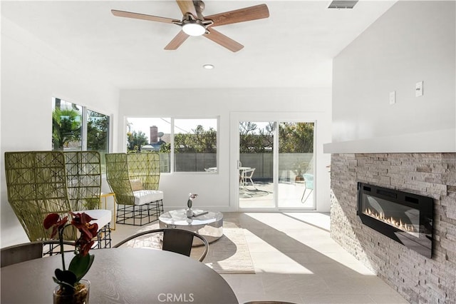 sunroom / solarium featuring ceiling fan and a stone fireplace