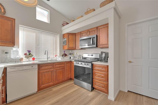 kitchen with sink, light wood-type flooring, lofted ceiling, and stainless steel appliances