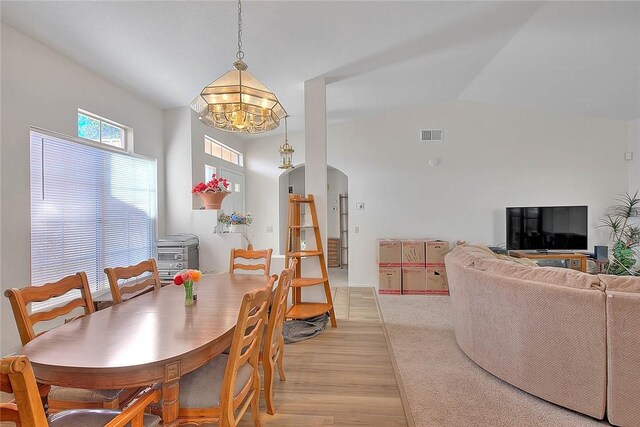 dining space featuring light hardwood / wood-style floors, a notable chandelier, and lofted ceiling